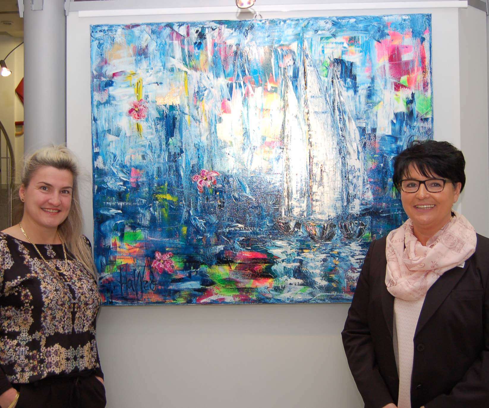 Das Foto zeigt die Künstlerin (links) zusammen mit Christiane Waldmannstetter, der stellvertretenden Filialleiterin in der Schlossstraße, anlässlich der Eröffnung der Ausstellung Anfang April 2019.