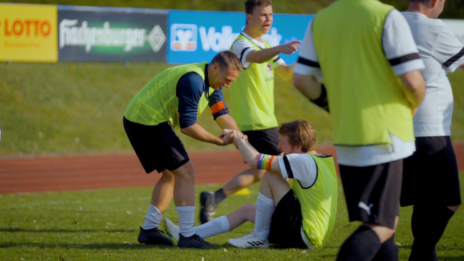 Fußballspieler hilft einem gestürzten Mitspieler auf