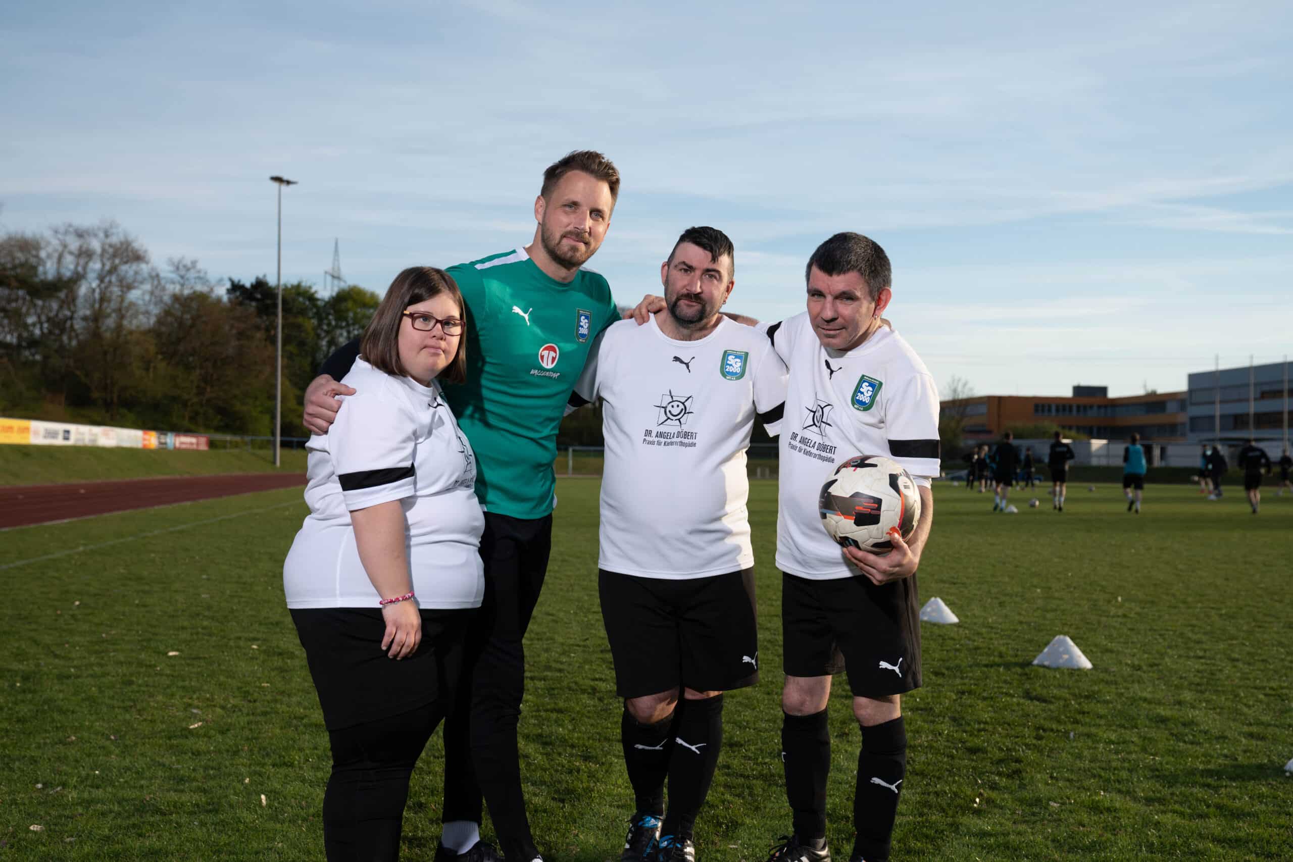 Trainer Michael Wall mit Fußballspielerin und Fußballspieler der Inklusionsmannschaft der SG 2000 Mülheim-Kärlich