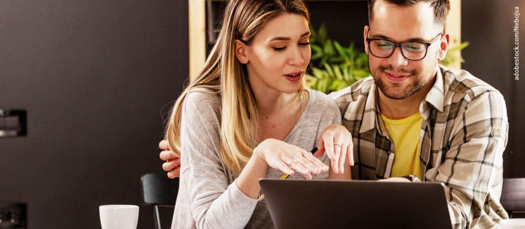 Junges Paar blickt auf einen Laptop